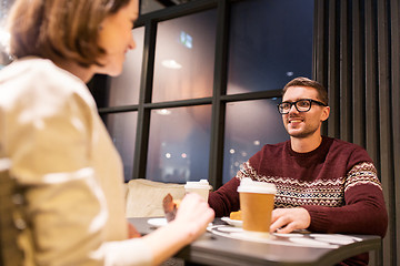 Image showing happy couple with coffee eating cake at cafe