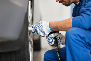 Image showing mechanic with screwdriver changing car tire