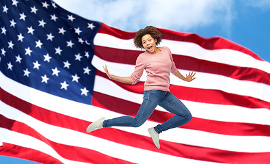 Image showing happy african woman jumping over american flag