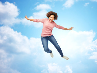 Image showing happy african american woman jumping over white