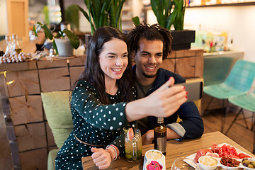 Image showing happy couple taking selfie at cafe or bar