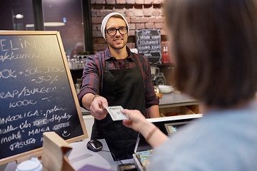 Image showing happy barman and woman paying money at cafe