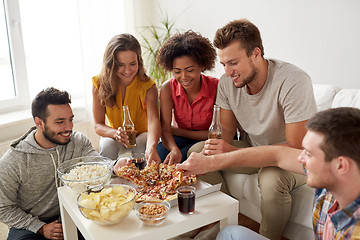 Image showing happy friends with drinks eating pizza at home