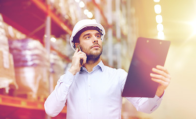 Image showing man with clipboard and smartphone at warehouse