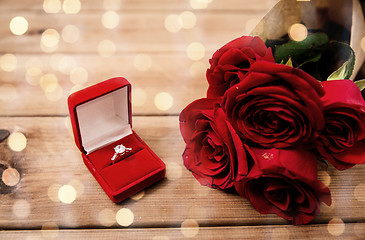 Image showing close up of diamond engagement ring and red roses