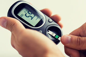 Image showing close up of man checking blood sugar by glucometer