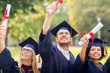 Image showing happy students in mortar boards with diplomas