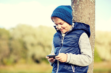 Image showing happy boy playing game on smartphone outdoors