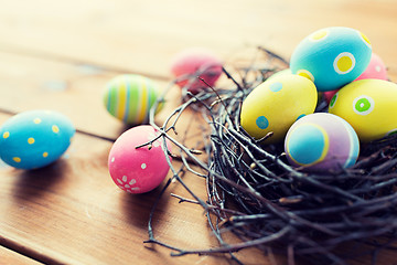 Image showing close up of colored easter eggs in nest on wood