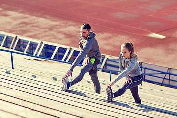 Image showing couple stretching leg on stands of stadium