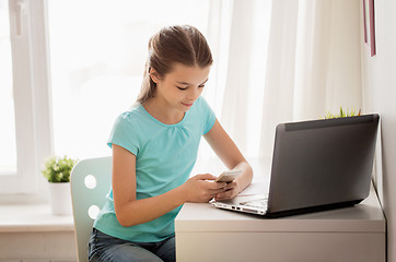 Image showing girl with laptop and smartphone texting at home