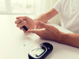 Image showing close up of man checking blood sugar by glucometer