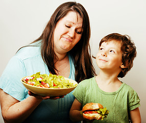 Image showing mature woman holding salad and little cute boy with hamburger te