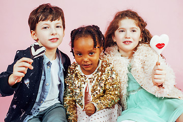 Image showing lifestyle people concept: diverse nation children playing together, caucasian boy with african little girl holding candy happy smiling 