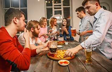 Image showing Group of friends enjoying evening drinks with beer