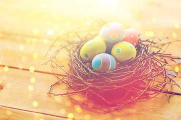 Image showing close up of colored easter eggs in nest on wood