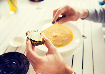 Image showing close up of hands applying butter to bread