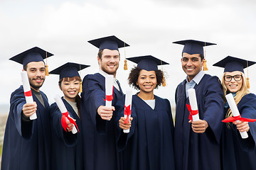 Image showing happy students in mortar boards with diplomas