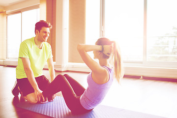 Image showing woman with personal trainer doing sit ups in gym