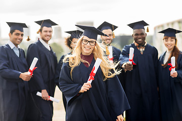 Image showing happy students in mortar boards with diplomas