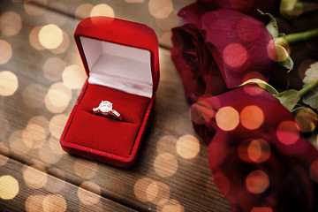 Image showing close up of diamond engagement ring and red roses