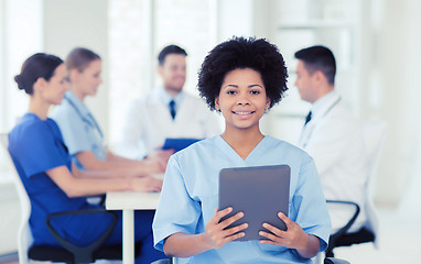 Image showing happy doctor with tablet pc over team at clinic