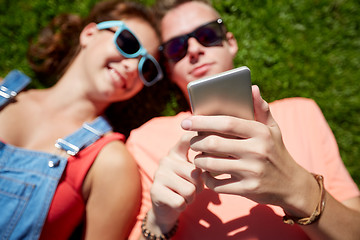 Image showing teenage couple with smartphone lying on grass