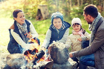 Image showing happy family roasting marshmallow over campfire