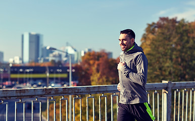 Image showing happy young man running over city bridge