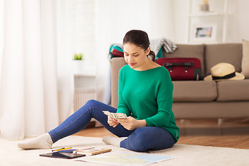 Image showing happy woman with money and travel map at home