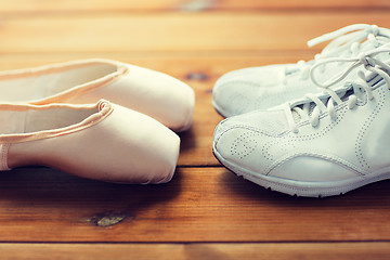 Image showing close up of sneakers and pointe shoes on wood