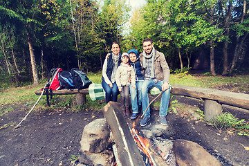 Image showing happy family sitting on bench at camp fire