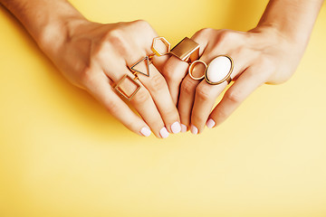 Image showing woman hands with manicure and jewelry ring on yellow background, beauty style concept