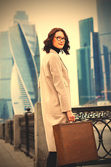 Image showing businesswoman in a bright coat and a wooden case
