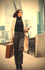 Image showing beautiful smiling middle-aged woman in a bright coat goes with a