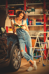 Image showing woman in blue overalls studying the instructions for vehicle adj