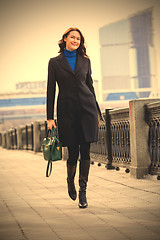 Image showing beautiful smiling woman in dark coat with handbag and laptop