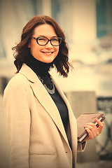 Image showing middle-aged woman in a bright coat with a books