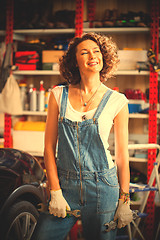 Image showing car mechanic smiling woman with wrenches standing near the car