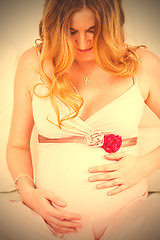 Image showing Beautiful pregnant woman looks at the belly