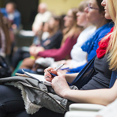 Image showing Hands holding pens and making notes at conference lecture.