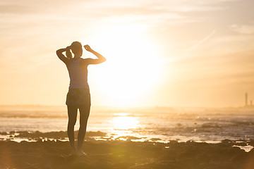 Image showing Woman on sandy beach watching sunset.