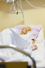 Image showing Bedridden female patient recovering after surgery in hospital care.