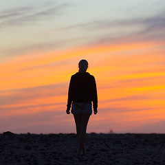 Image showing Woman on rocky beach watching sunset.