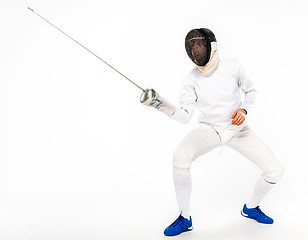 Image showing Man wearing fencing suit practicing with sword against gray