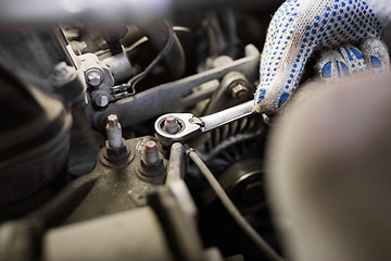 Image showing mechanic man with wrench repairing car at workshop