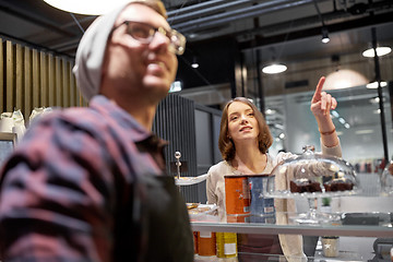 Image showing happy woman showing something to bartender at cafe