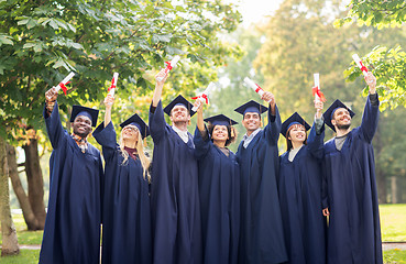 Image showing happy students in mortar boards with diplomas