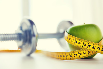 Image showing close up of dumbbell and apple with measuring tape