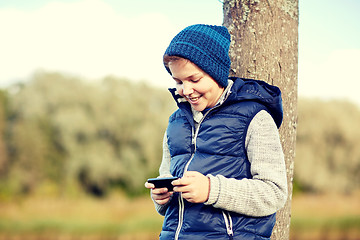 Image showing happy boy playing game on smartphone outdoors